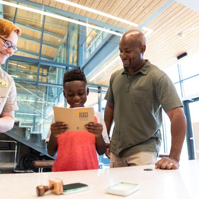 Father and son getting their passport stamped by a state park interpreter